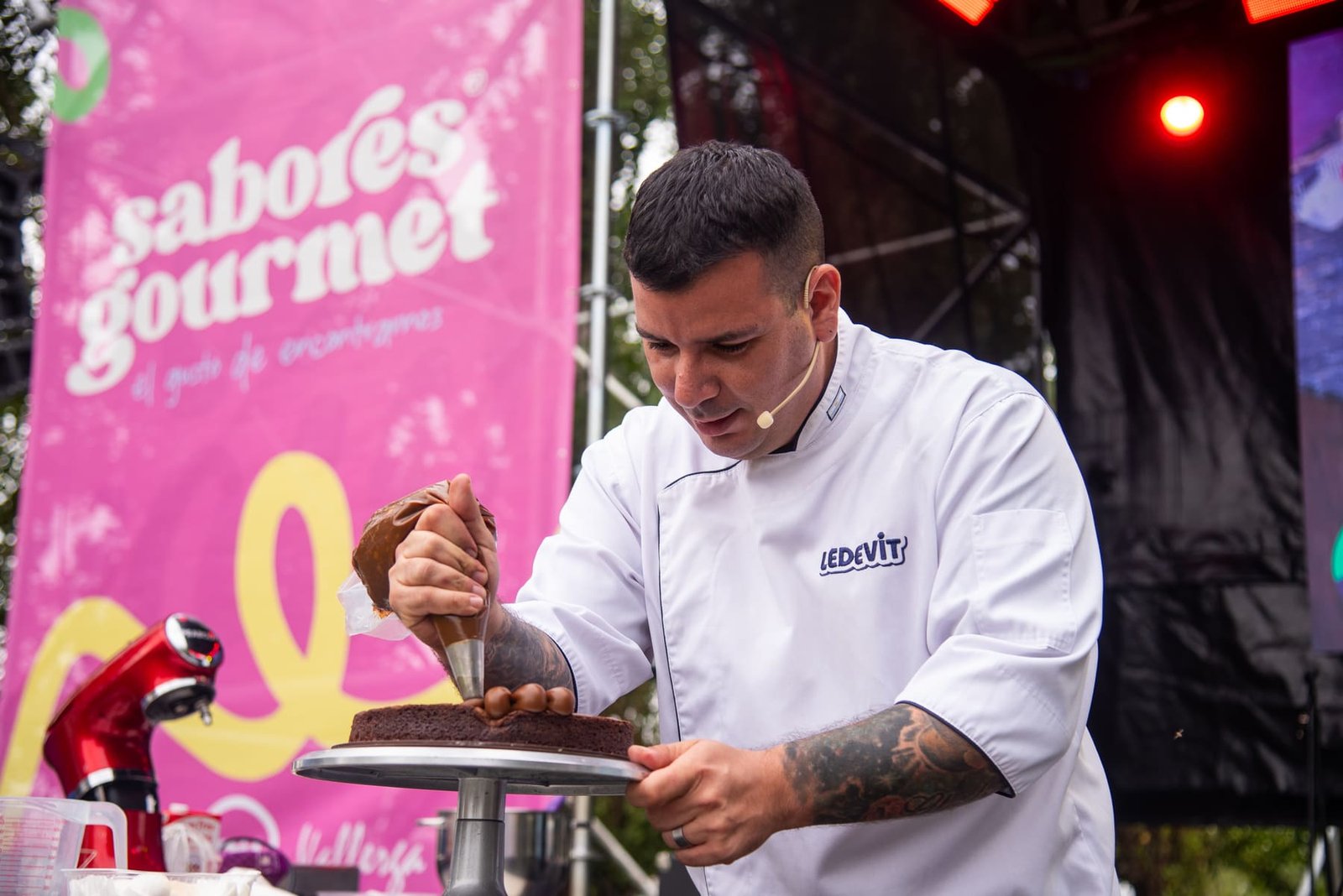 Chef pastelero decorando una torta en vivo sobre el escenario de Sabores Gourmet