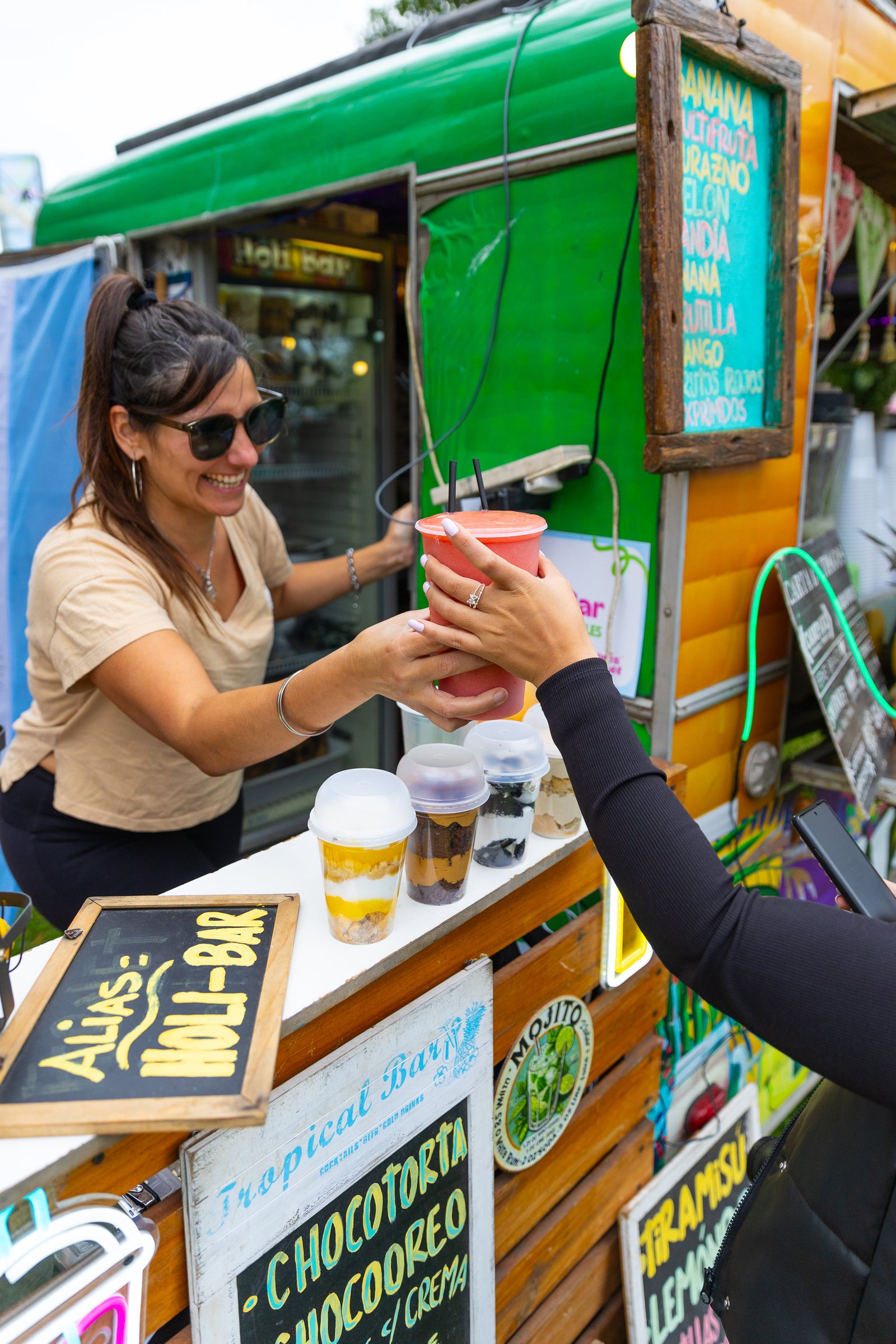 Empleada de un food truck entregando un licuado a una clienta