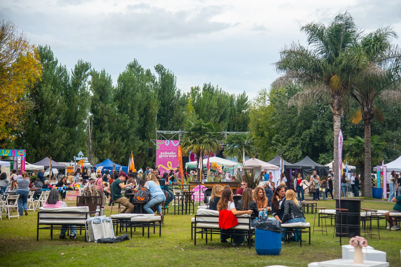 Vista panorámica del predio con el escenario de Sabores Gourmet y puestos entre palmeras