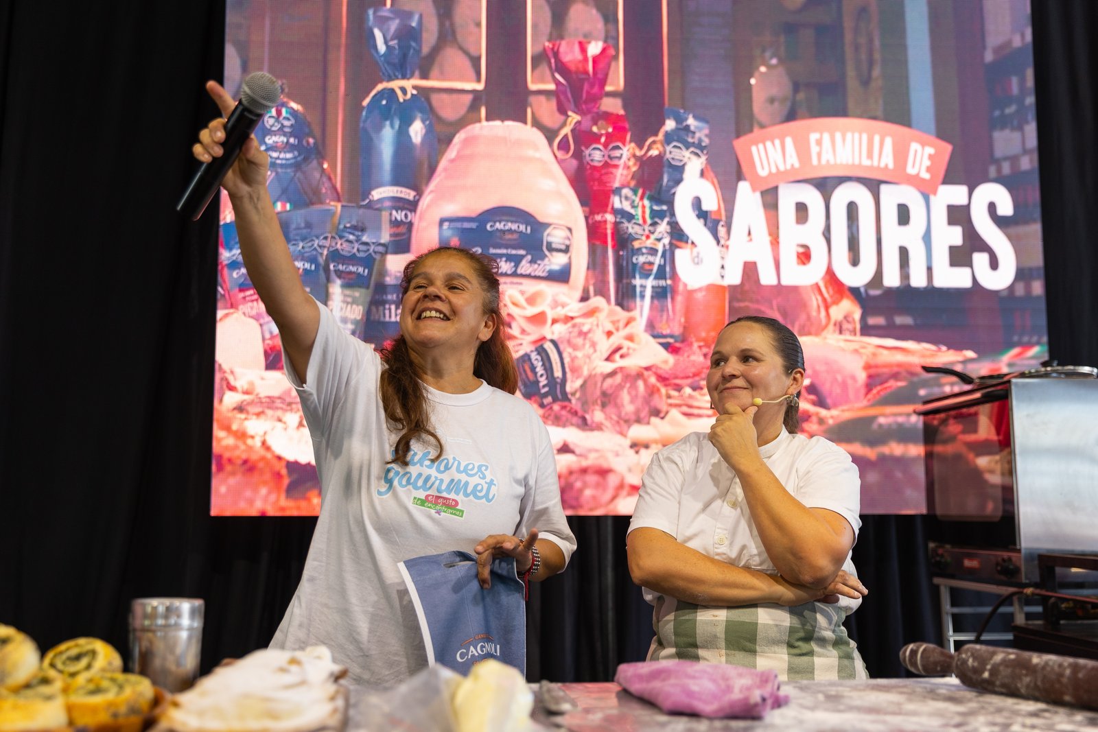 Dos cocineras sobre el escenario con la pantalla que dice Una familia de sabores